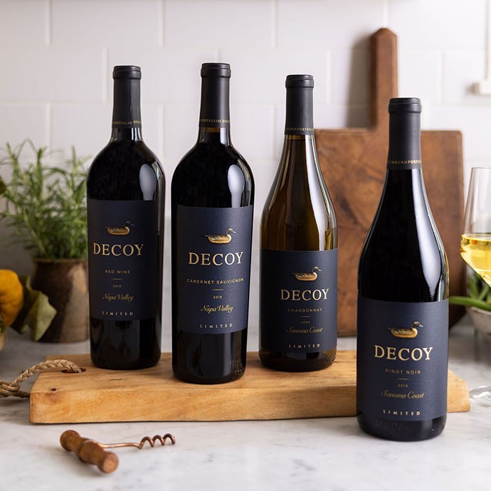 Four bottles of Decoy Limited wine bottles on white counter with herbs