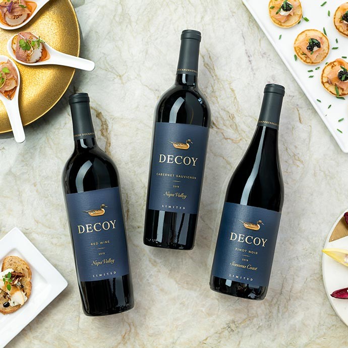 Three bottles of Decoy Limited wine bottles on white counter with food